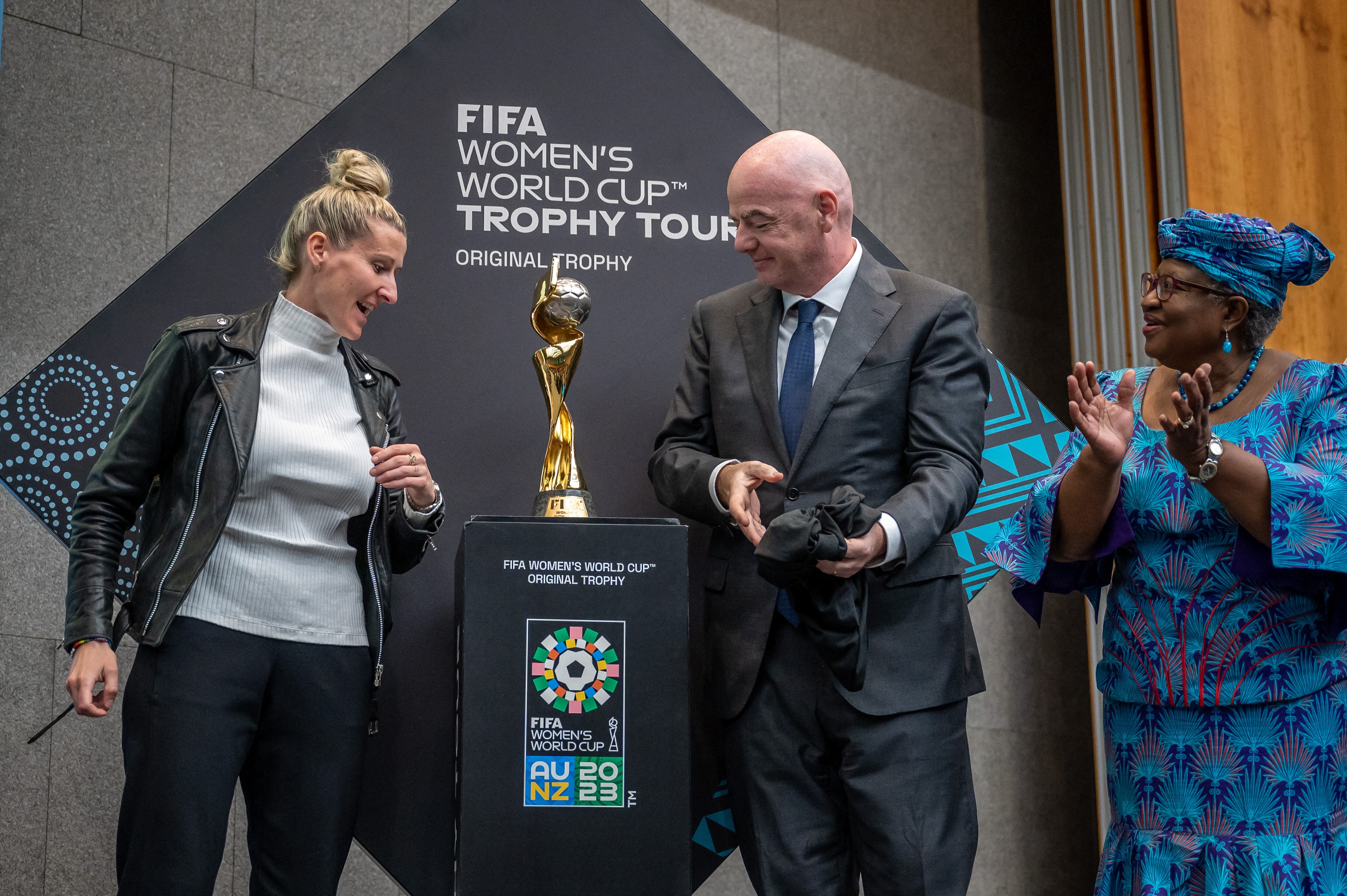 (From L) German football legend Anja Mittag, FIFA President Gianni Infantino and World Trade Organization (WTO) Director-General Ngozi Okonjo-Iweala unveil the FIFA Women's World Cup trophy during the "Making trade score for women!" discussion on football as a tool for trade and development at the WTO headquarters in Geneva, on May 1, 2023. (Photo by Fabrice COFFRINI / AFP)