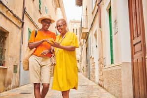 Viajeros usando una aplicación móvil en su teléfono inteligente para guiarse por un casco antiguo tradicional de Mallorca, España.