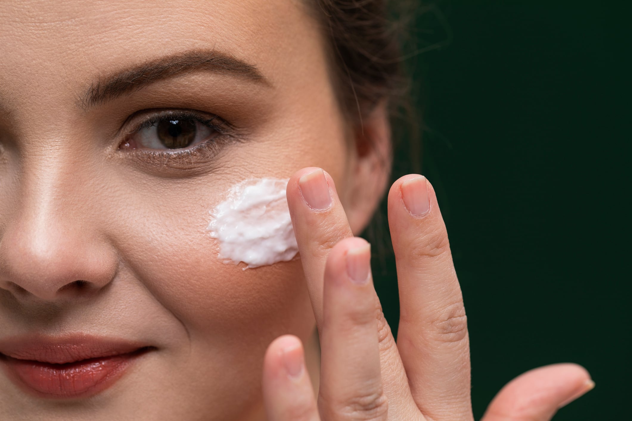 A young Caucasian overweight woman applying face cream as part of her daily routine.