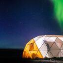 Carpa domo iluminada con aurora boreal en el fondo, en Narsaq Vestgronland, un lugar ubicado en Groenlandia