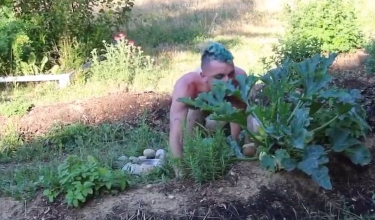 Un hombre completamente desnudos se mueve entre las plantas, mientras otros observan