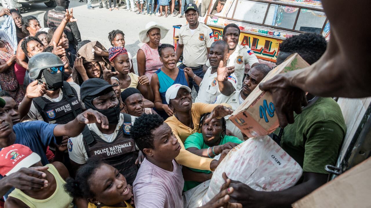 Los policías monitorean a la multitud mientras las víctimas del terremoto reciben suministros durante la distribución de alimentos y agua en el cruce de "4 Chemins" en Les Cayes, Haití, el 20 de agosto de 2021. - El número de muertos en el gran terremoto que golpeó a Haití el 14 de agosto de 2021 ha aumentado a 2.207, dijeron las autoridades el 22 de agosto de 2021, ya que los ataques a los convoyes de ayuda han complicado los esfuerzos para brindar ayuda a los sobrevivientes. "Se han encontrado nuevos cuerpos en el sur", dijo un comunicado de la oficina de protección civil del país, agregando que 344 personas permanecen desaparecidas y 12.268 han sido catalogadas como heridas. La cifra reportada anteriormente fue de 2.189 muertos. (Foto de Reginald LOUISSAINT JR / AFP)