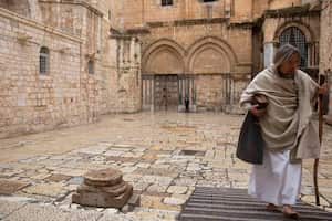 Un cristiano pasa junto a la Iglesia del Santo Sepulcro, que, según muchos cristianos, es el lugar de la crucifixión y sepultura de Jesucristo, en Jerusalén, el viernes 10 de abril de 2020. Los cristianos conmemoran la crucifixión de Jesús sin los solemnes servicios de la iglesia o procesiones emocionales de años pasados, que marcan el Viernes Santo en un mundo encerrado por la pandemia de coronavirus. AP Photo/Sebastian Scheiner