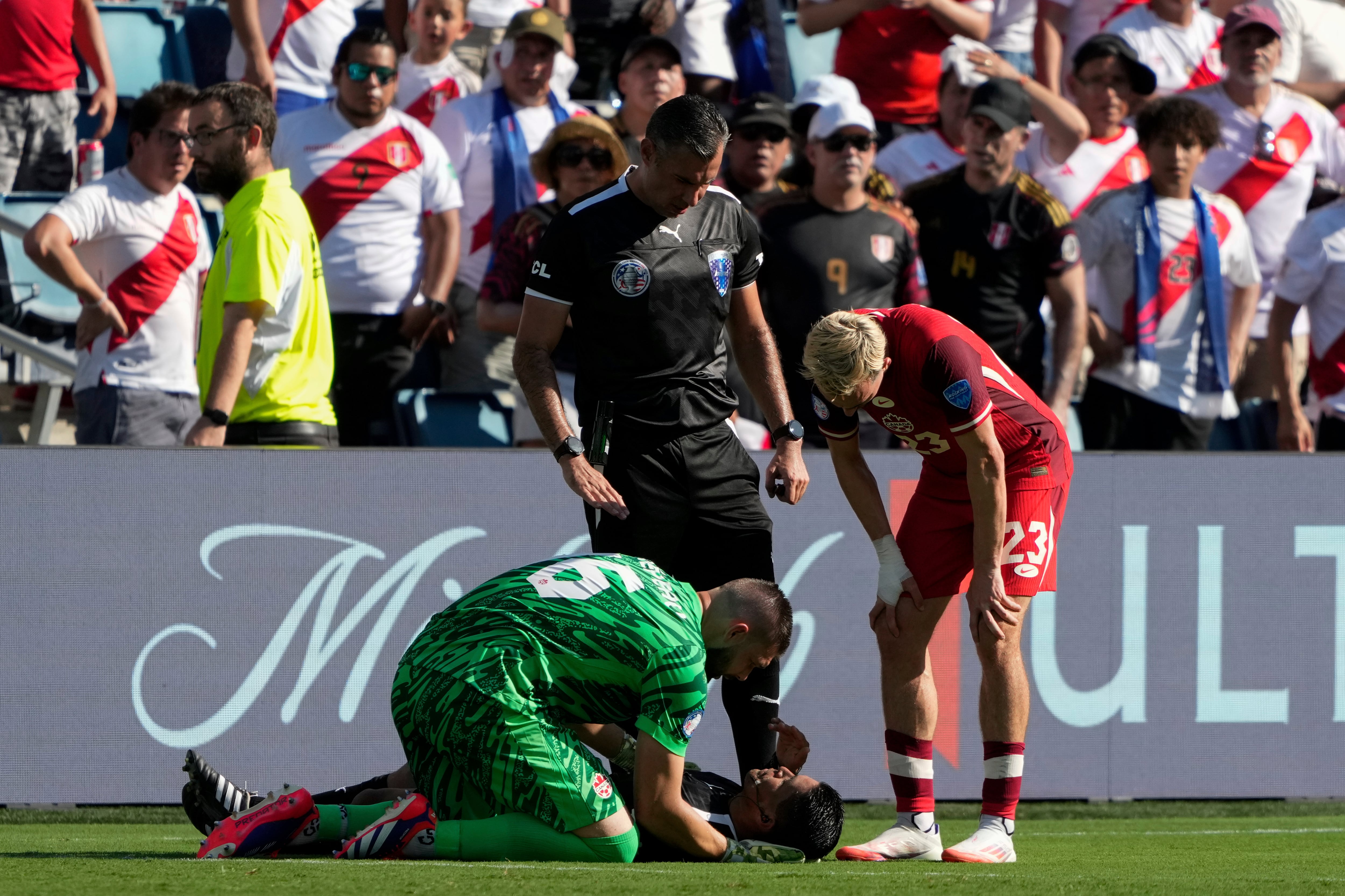 Canada's goalkeeper Maxime Crepeau, his teammate Liam Millar, right, and referee  Mario Escobar, of Guatemala, tend to assistant referee Humberto Panjoj after he fainted during a Copa America Group A soccer match in Kansas City, Kan., Tuesday, June 25, 2024. (AP Photo/Ed Zurga)