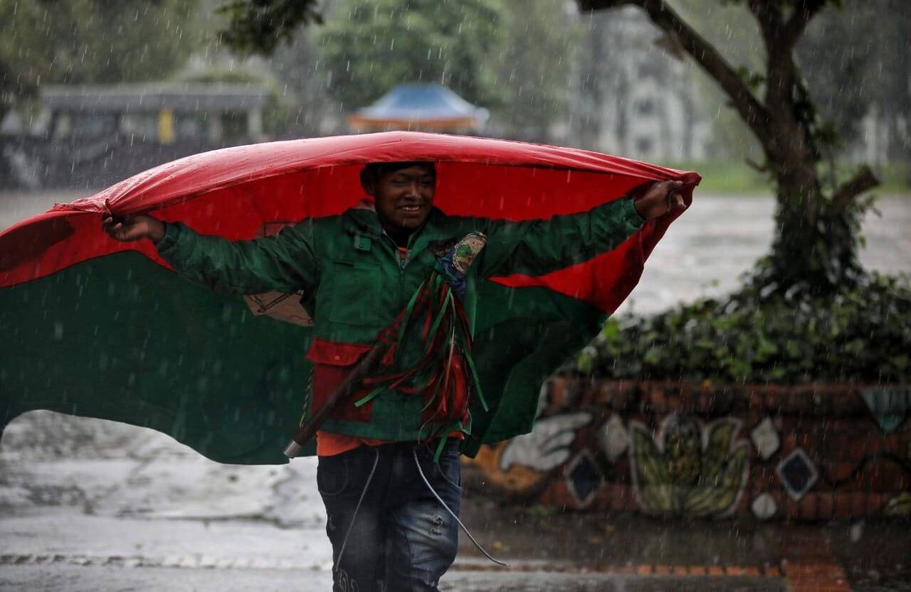 La bandera sirvió como paraguas para este indígena que corrió para buscar un techo. Foto: Esteban Vega /Semana.