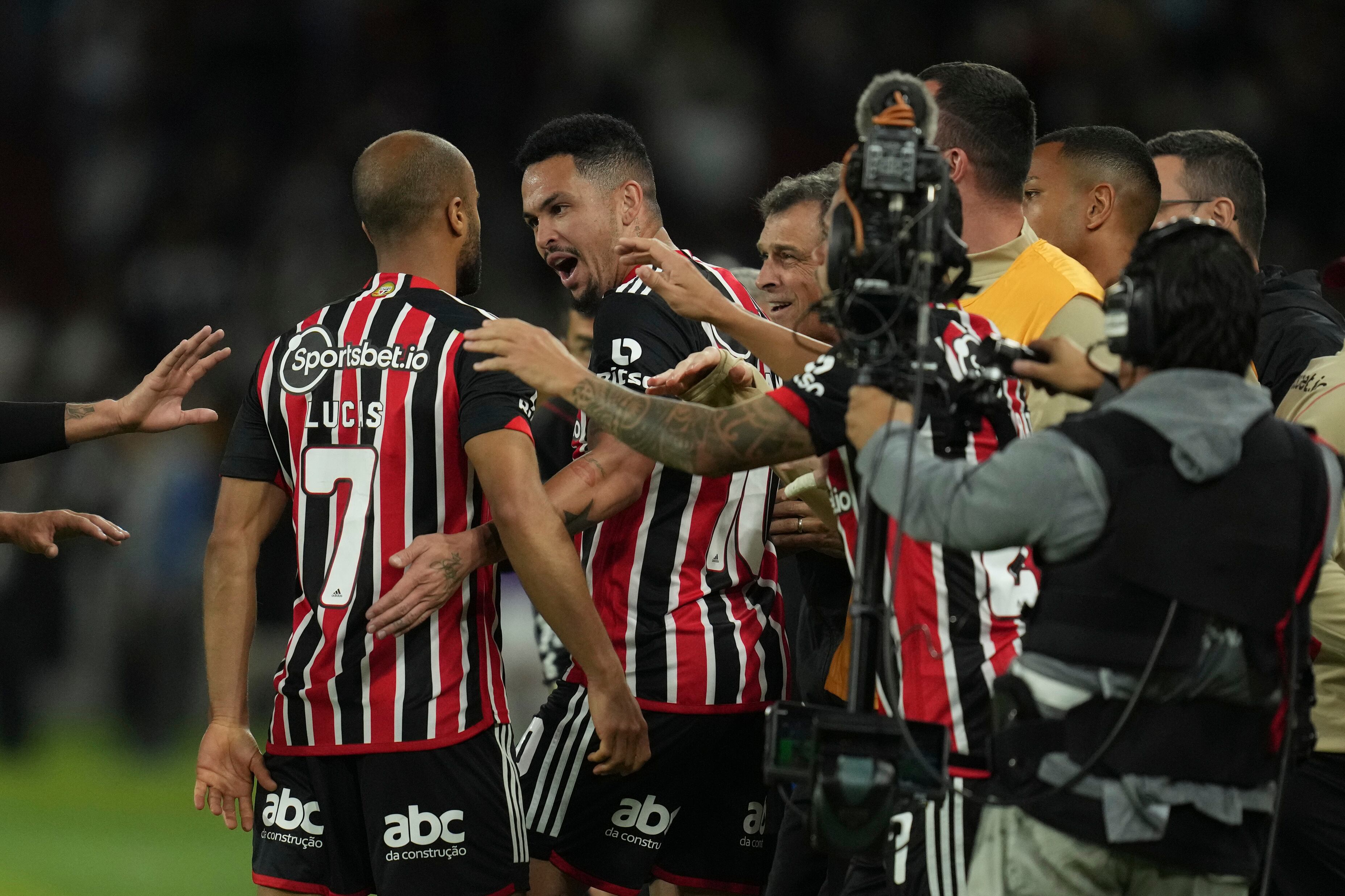 Lucas Moura, left, of Brazil's Sao Paulo is congratulated by his teammate Luciano and the bench after scoring his team's only goal against Ecuador's Liga Deportiva Universitaria during a Copa Sudamericana quarterfinal, first leg soccer match at Rodrigo Paz Delgado stadium in Quito, Ecuador, Thursday, Aug. 24, 2023. (AP Photo/Dolores Ochoa)