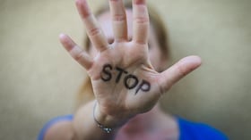 Enfoque selectivo en la mano abierta de una mujer con una señal de stop escrita.