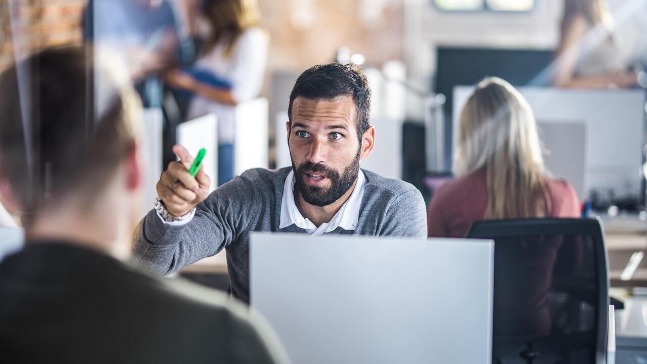 Businessman communicating with his colleague while working at corporate office. The view is through glass.