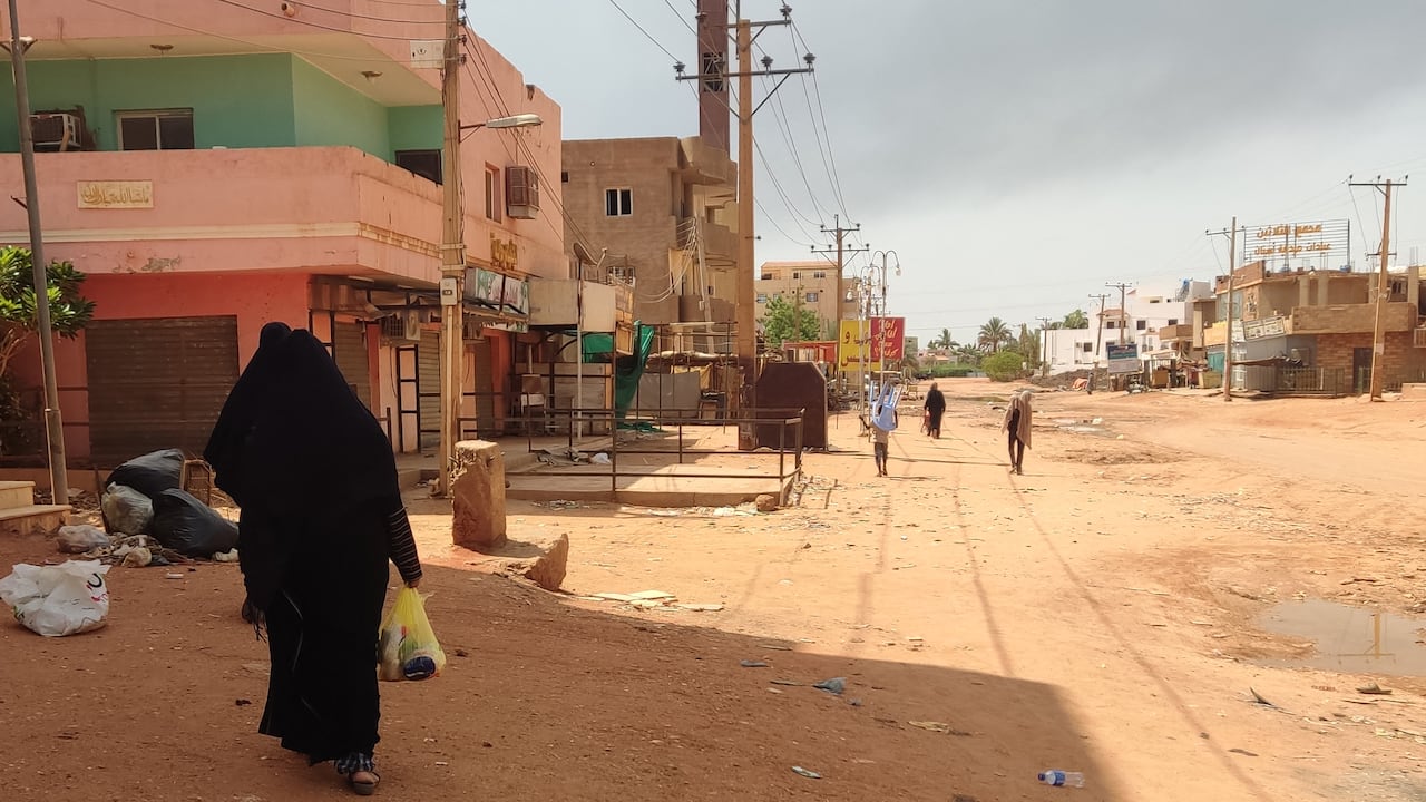 La gente camina frente a las tiendas en Jartum el 9 de junio de 2023, en medio de los combates en curso.