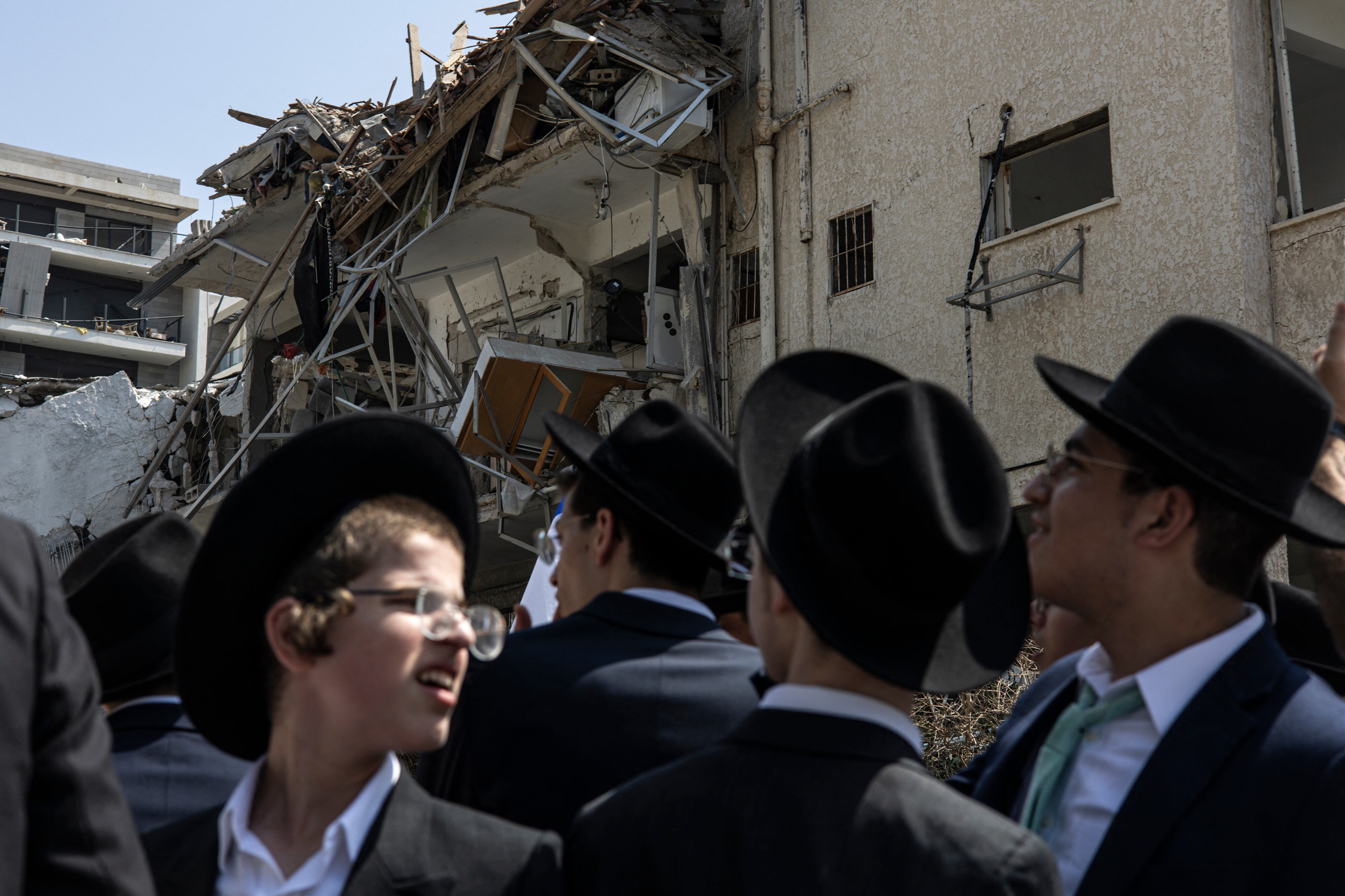 Ultra-Orthodox Jewish men look on at a site in Tel Aviv hit by a missile fired from Iran on June 14, 2025. Israel's military said that its fighter jets were set to resume striking targets in Tehran, after announcing it had hit air defences in the Iranian capital area overnight, as Israel and Iran trade fire with such intensity for the first time following decades of enmity and conflict by proxy, with fears of a prolonged conflict engulfing the region. (Photo by JOHN WESSELS / AFP)