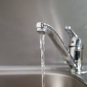 Agua que corre de un grifo a un fregadero. Fotografía de cerca