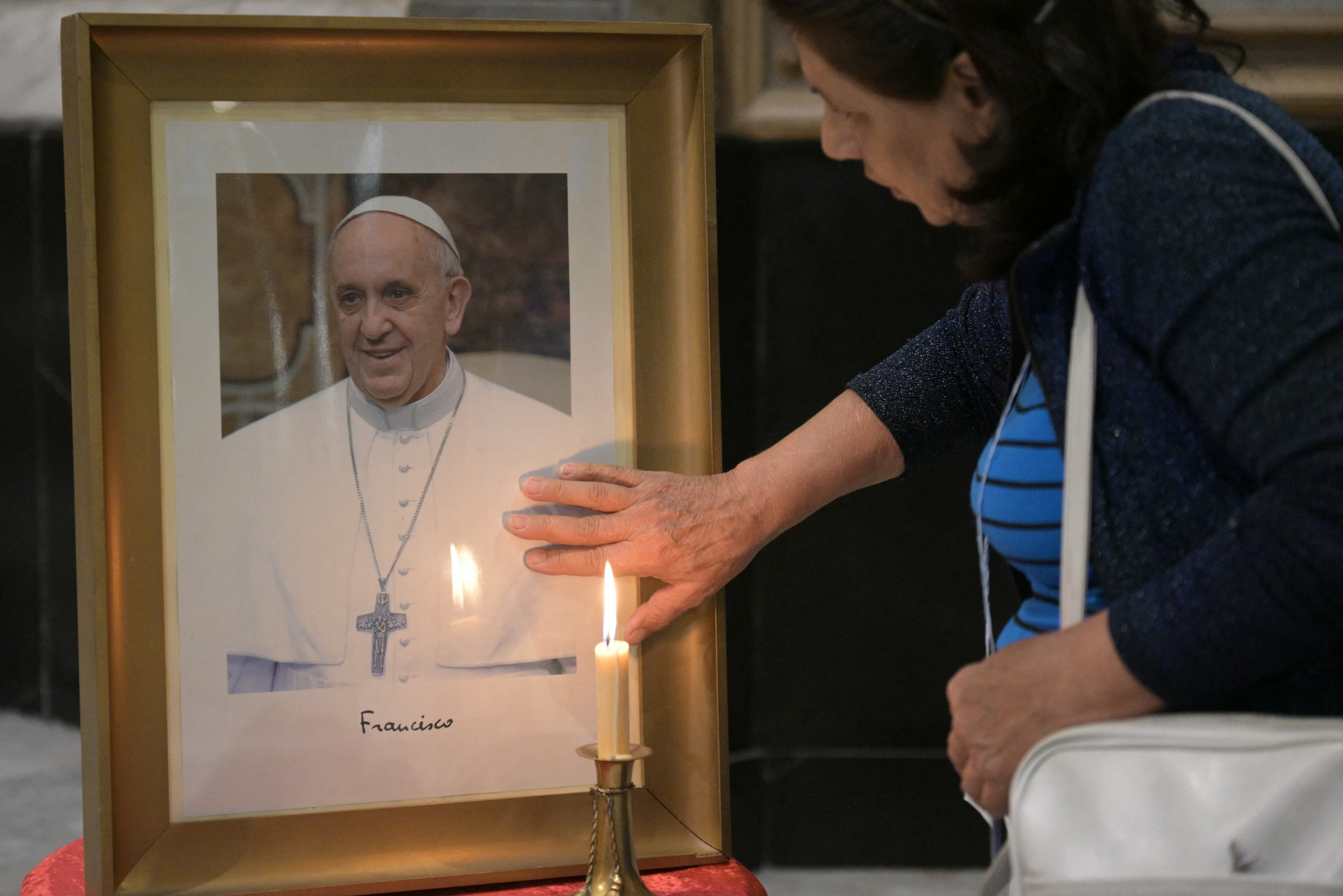 Un fiel toca un retrato del papa Francisco durante una misa en la Basílica San José de Flores para rezar por su salud en Buenos Aires el 19 de febrero de 2025. (Foto de JUAN MABROMATA / AFP)