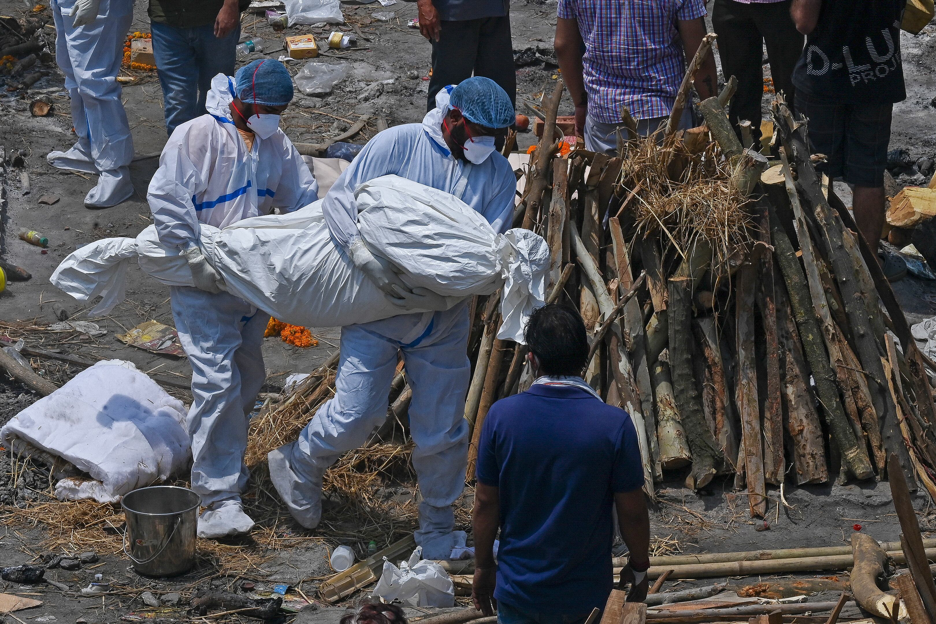 Familiares y trabajadores de salud cargan los cuerpos de muertos por covid-19 en un centro masivo de cremación, New Delhi, India, 27 de abril