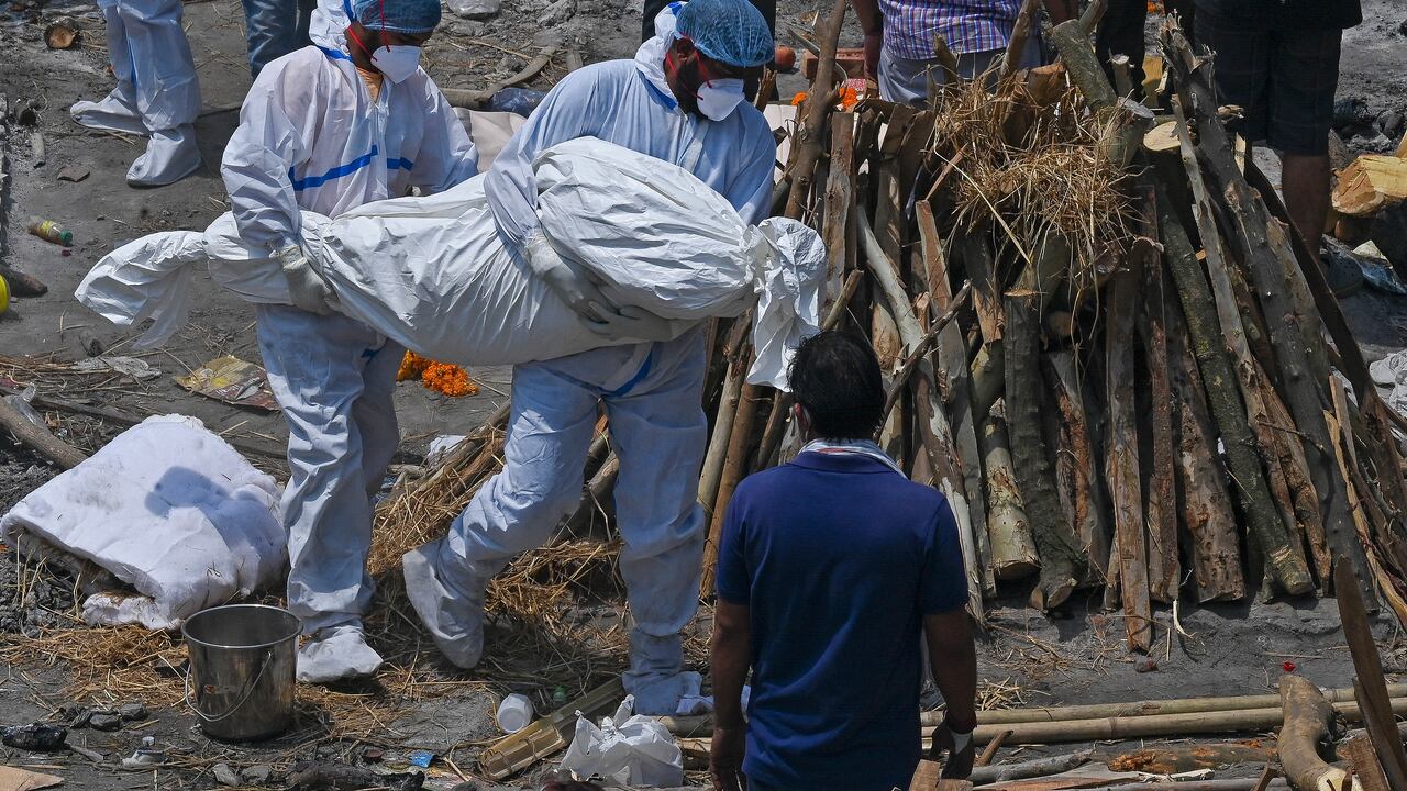 Familiares y trabajadores de salud cargan los cuerpos de muertos por covid-19 en un centro masivo de cremación, New Delhi, India, 27 de abril