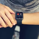 Mujer joven que controla el reloj deportivo que mide la frecuencia cardíaca y el rendimiento después de correr.