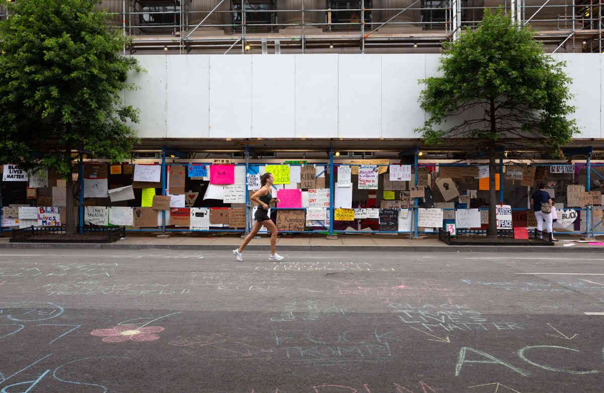 Una corredora pasa enfrente de la construcción cruzando la calle de la reja que rodea Lafayette Square. Voluntarios y activistas de ONGs recxolocaron los letreros dejados por manifestantes durante los días previos sobre la reja que sería retirada el 11 de Junio. Imagen tomada el 10 de Junio de 2020 , Washington DC- Foto María Luz Bravo