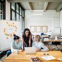 Tres mujeres empresarias jóvenes casuales que tienen una reunión con un portátil en un loft de oficina moderno