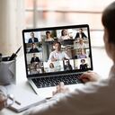Vista sobre el hombro de la mujer de negocios sentada en el escritorio del lugar de trabajo, mire la pantalla de la computadora donde hay un collage de muchas personas diversas involucradas en la actividad de negociaciones de videoconferencia, concepto moderno de uso de tecnología de aplicaciones