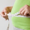 Mujer gorda con sobrepeso midiendo su cintura. Talla extra. Nuevo comienzo para un estilo de vida saludable, adelgazamiento corporal y pérdida de peso. Preocuparse por el cuerpo. Copie el espacio. Lugar vacío para texto sobre fondo gris.