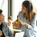 Profesor maduro explicando a los estudiantes en el aula. Hombres y mujeres están escuchando al profesor en la universidad. Están sentados a la mesa.