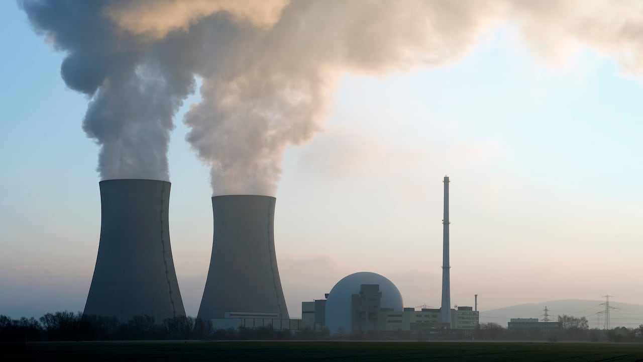 Central nuclear con torres de enfriamiento humeantes al amanecer. Imagen de referencia