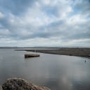 Boat anchored in a sea inlet surrounded by sand and stones on a beach in Barranquilla. Colombia.