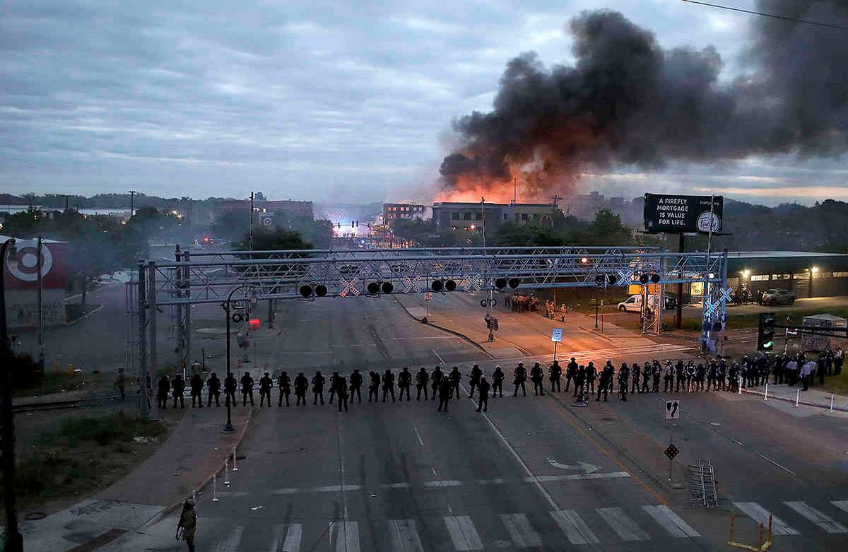 Los agentes de la ley se congregaron a lo largo de Lake Street, cerca de la avenida Hiawatha, mientras ardían incendios después de una noche de disturbios y protestas por la muerte de George Floyd quien murió después de ser retenido por oficiales de policía de Minneapolis en el Día de los Caídos. (David Joles / Star Tribune a través de AP)