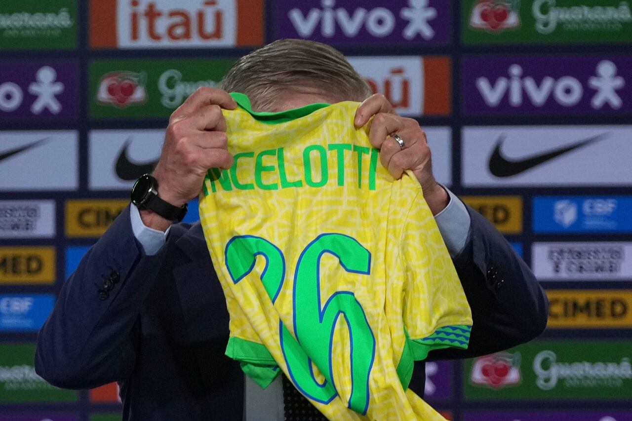 Brazil's new national soccer team head coach Carlo Ancelotti holds a national team jersey he received as a gift during a news conference to announce the players who will compete in the World Cup qualifiers against Ecuador and Paraguay, in Rio de Janeiro, Monday, May 26, 2025. (AP Photo/Silvia Izquierdo)