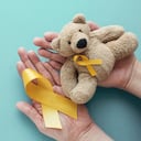 Manos sosteniendo a los niños oso pardo de juguete suave con cinta de oro amarillo, conciencia del cáncer infantil