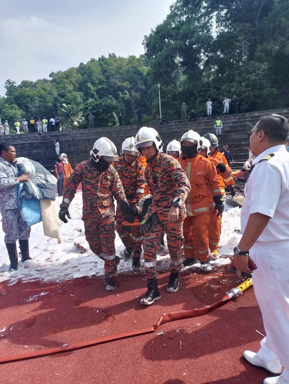 El personal de emergencia transporta el cuerpo de una víctima de un accidente de helicóptero en Lumut, Perak, Malasia, el 23 de abril de 2024. Departamento de Bomberos y Rescate de Malasia