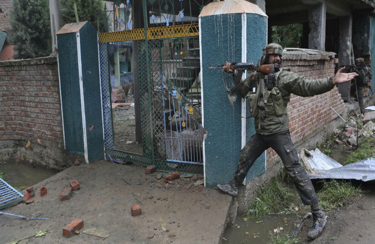 Un soldado de la India pide a gritos a sus compañeros que le tiren un cartucho con balas durante un enfrentamiento en Rajporta, al sur de la India. (AP)