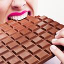 Mujer en lápiz labial rosa mordiendo una gran barra de chocolate