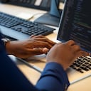 Primer plano de la codificación del empresario en la computadora portátil en su escritorio. Programador informático que trabaja en la computadora portátil que hace un nuevo programa de software.