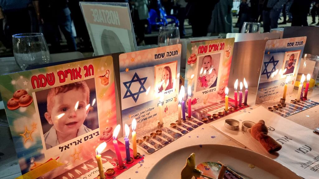 TEL AVIV, ISRAEL - DECEMBER 9: Hanukkah candles are lit at places set at the festival table for the Bibas family, an Israeli family including 11-month-old baby Kfir, his 4-year-old brother Ariel and their parents Shiri and Yarden, who are being held hostage by Hamas in the Gaza Strip, in The Hostages and Missing Square, on December 9, 2023 in Tel Aviv, Israel. Thousands of Israelis called for the immediate release of the remaining 138 Israeli hostages held by Hamas during a rally in the square, which coincided with the third night of the Jewish festival of Hanukkah. (Photo by David Silverman/Getty Images)