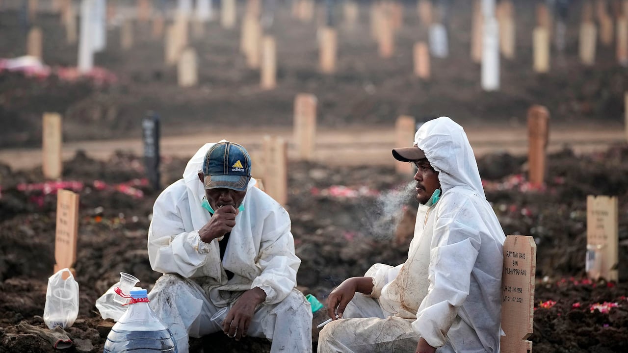 Los trabajadores toman un descanso durante un día ajetreado en el cementerio de Rorotan, que está reservado para los que murieron de COVID-19, en Yakarta, Indonesia - Foto: AP / Dita Alangkara.