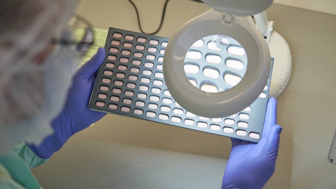 En esta foto proporcionada por Pfizer, un técnico de laboratorio inspecciona visualmente muestras de tabletas de Paxlovid en Freiburg, Alemania, en diciembre de 2021. (Pfizer via AP)