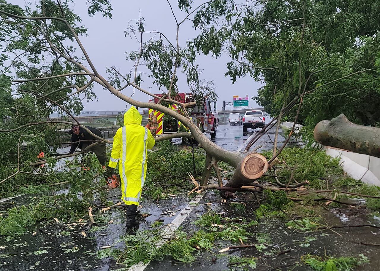 En esta foto proporcionada por el Negociado del Departamento de Bomberos de Puerto Rico el 18 de septiembre de 2022, los bomberos trabajan para retirar un árbol caído de la carretera en Vega Baja, Puerto Rico. - El huracán Fiona se precipitó hacia la costa de Puerto Rico el domingo, dejando sin electricidad y amenazando con causar "inundaciones catastróficas" en el territorio de la isla estadounidense. (Foto del Negociado del Departamento de Bomberos de Puerto Rico / AFP) / RESTRINGIDO A USO EDITORIAL - CRÉDITO OBLIGATORIO "FOTO AFP / Negociado del Departamento de Bomberos de Puerto Rico" - SIN MARKETING - SIN CAMPAÑAS PUBLICITARIAS - DISTRIBUIDO COMO SERVICIO A CLIENTES
