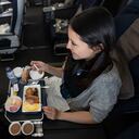 Una mujer viaja en avión y come a bordo - conceptos de viaje