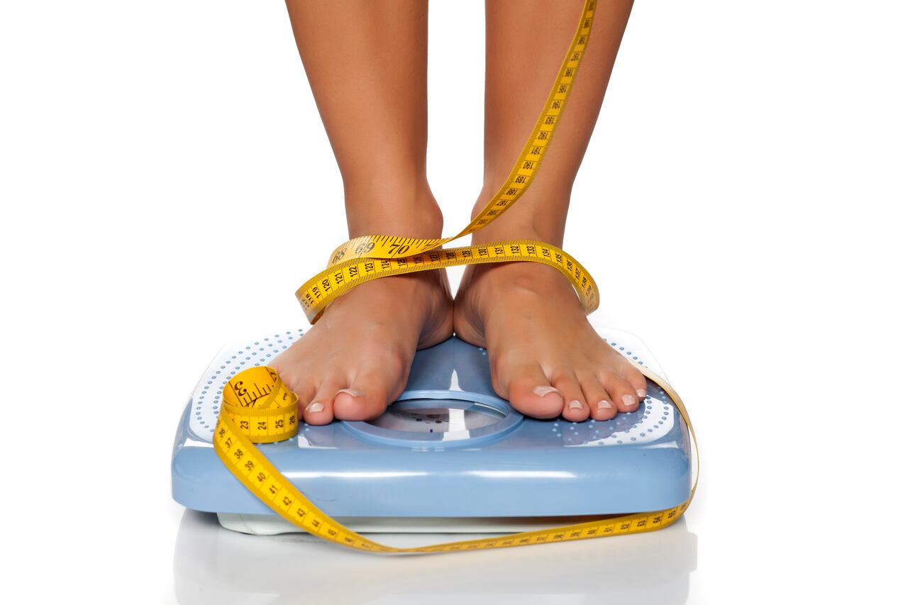 woman's feet on a domestic weight scale and measuring tape around them