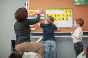 Profesora enseñando a estudiantes en los primeros años.