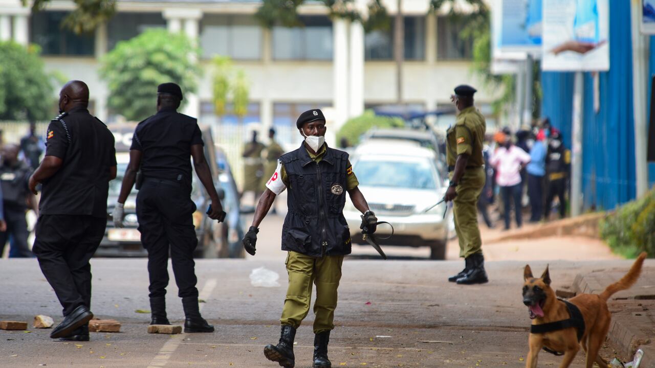 Un policía camina atrás de un perro rastreador en una calle cerca de una explosión en el centro de Kampala, Uganda, el martes 16 de noviembre de 2021. (AP Foto/Nicholas Bamulanzeki)