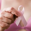 Mujer en sujetador rosa sosteniendo una cinta rosa, un recordatorio de la importancia del examen de mama en la atención médica para mantener y mantener un estilo de vida saludable y libre de cáncer
