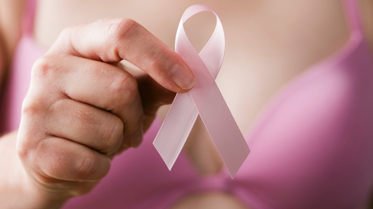 Mujer en sujetador rosa sosteniendo una cinta rosa, un recordatorio de la importancia del examen de mama en la atención médica para mantener y mantener un estilo de vida saludable y libre de cáncer