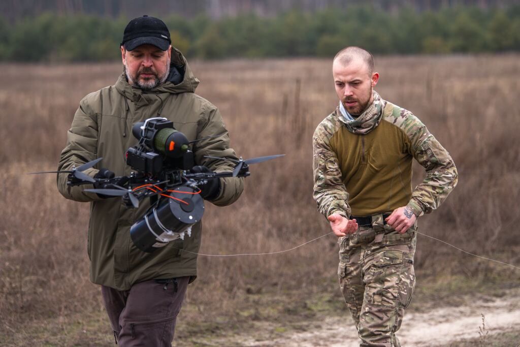 KYIV OBLAST, UKRAINE - JANUARY 29: Ukrainian servicemen carry an FPV drone controlled via a fiber-optic cable in a field during Ukrainian military training on January 29, 2025 in Kyiv Oblast, Ukraine. Using FPV drones controlled via a fiber-optic cable makes it possible to ignore the operation of electronic warfare, because a pilot has a direct connection with a drone through a fiber-optic cable. (Photo by Dan Bashakov/Global Images Ukraine via Getty Images)