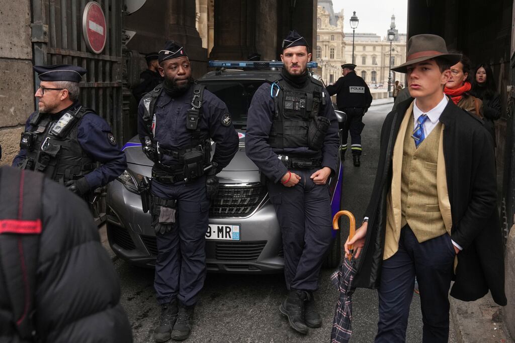 FILE - Pedro Elias Garzon Delvaux, right, walks past as police officers block an entrance to the Louvre after thieves carried out a daylight raid on French crown jewels, in Paris, Oct. 19, 2025. (AP Photo/Thibault Camus, File)