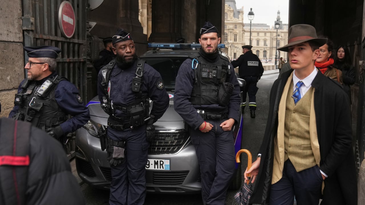 FILE - Pedro Elias Garzon Delvaux, right, walks past as police officers block an entrance to the Louvre after thieves carried out a daylight raid on French crown jewels, in Paris, Oct. 19, 2025. (AP Photo/Thibault Camus, File)