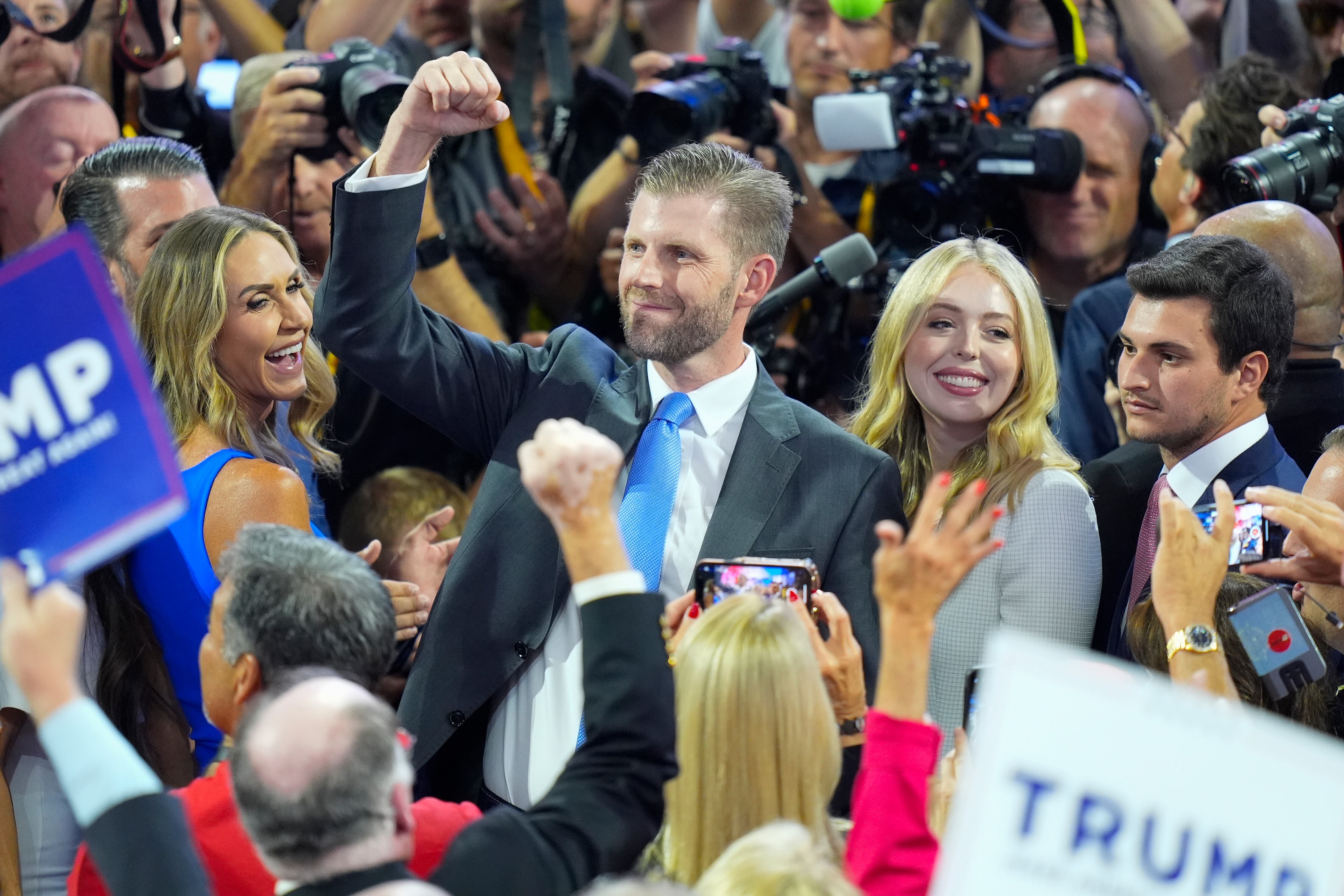 Eric Trump, center, raises his arm during roll call of the states during the first day of the Republican National Convention, Monday, July 15, 2024, in Milwaukee. Also with him are from l-r., his wife Lara Trump, Tiffany Trump, and her husband Michael Boulos. (AP Photo/J. Scott Applewhite)