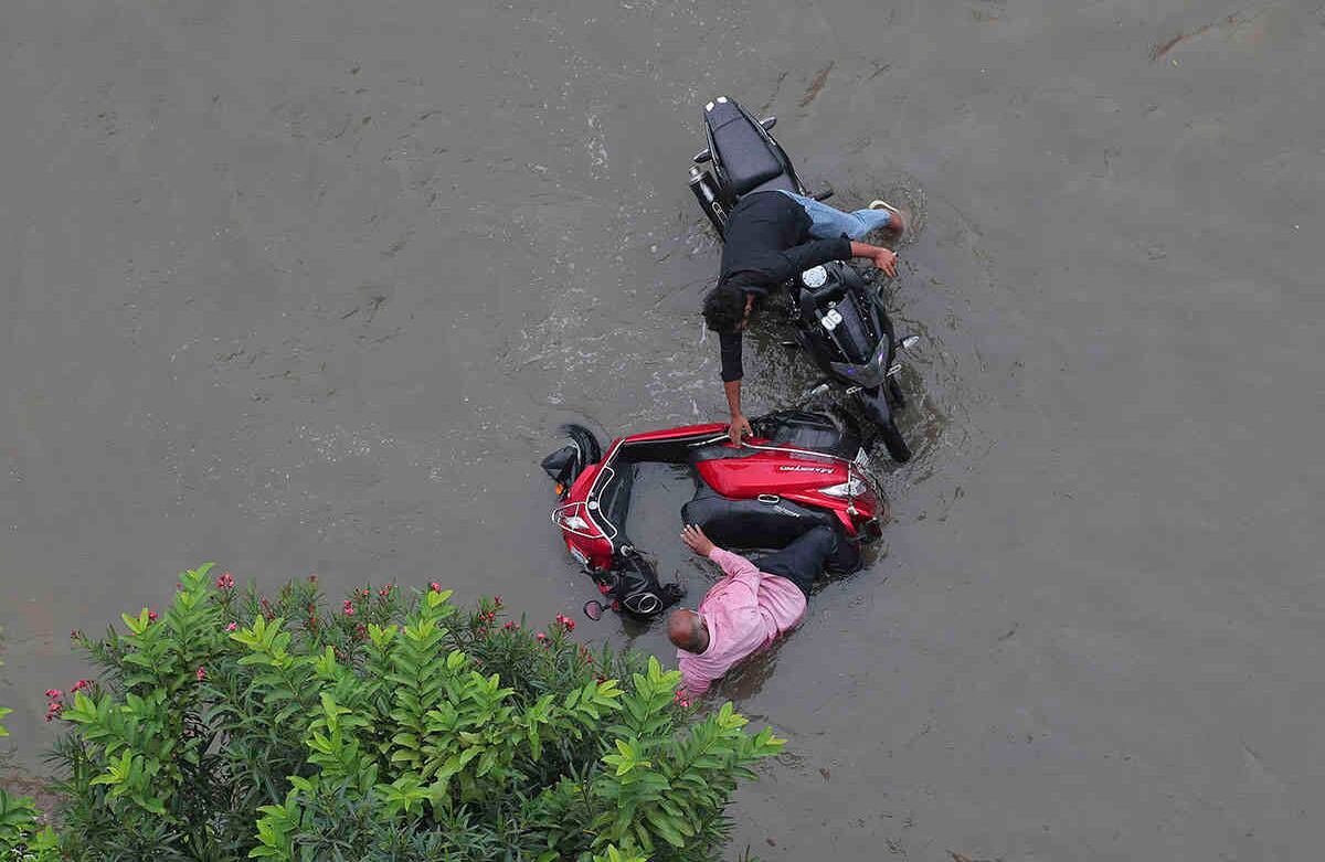 Un motociclista intenta ayudar a otro que cayó al agua en una calle inundada durante las lluvias monzónicas en Hyderabad, India, el 20 de agosto. India recibe sus lluvias monzónicas de junio a septiembre. Foto: Mahesh Kumar / AP