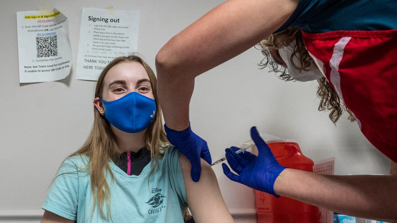 Audrey Vakker, de 14 años, observa cómo recibe la vacuna Covid-19 en la clínica de vacunación del Fairfax Government Center en Fairfax, Virginia, el 13 de mayo de 2021. (Photo by ANDREW CABALLERO-REYNOLDS / AFP)
