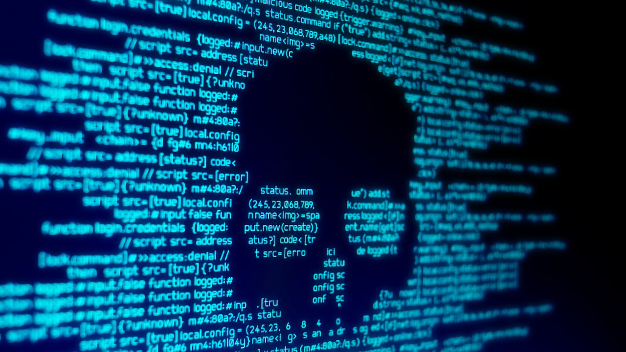 Código de computadora en una pantalla con una calavera que representa un ataque de malware/virus informático.